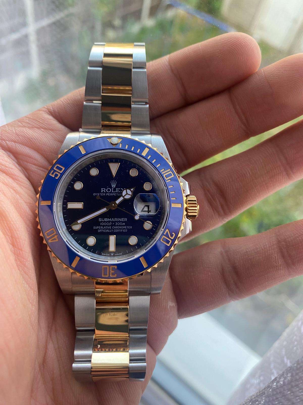 A Rolex Submariner luxury watch with a striking blue dial and two-tone gold and stainless steel bracelet.